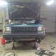 The XJ sits in a garage as its suspension parts are removed.